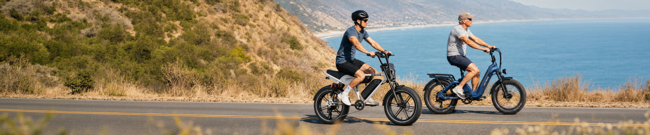 Two riders on Heybike Titan and Ranger S e-bikes on a coastal road, official Heybike photo