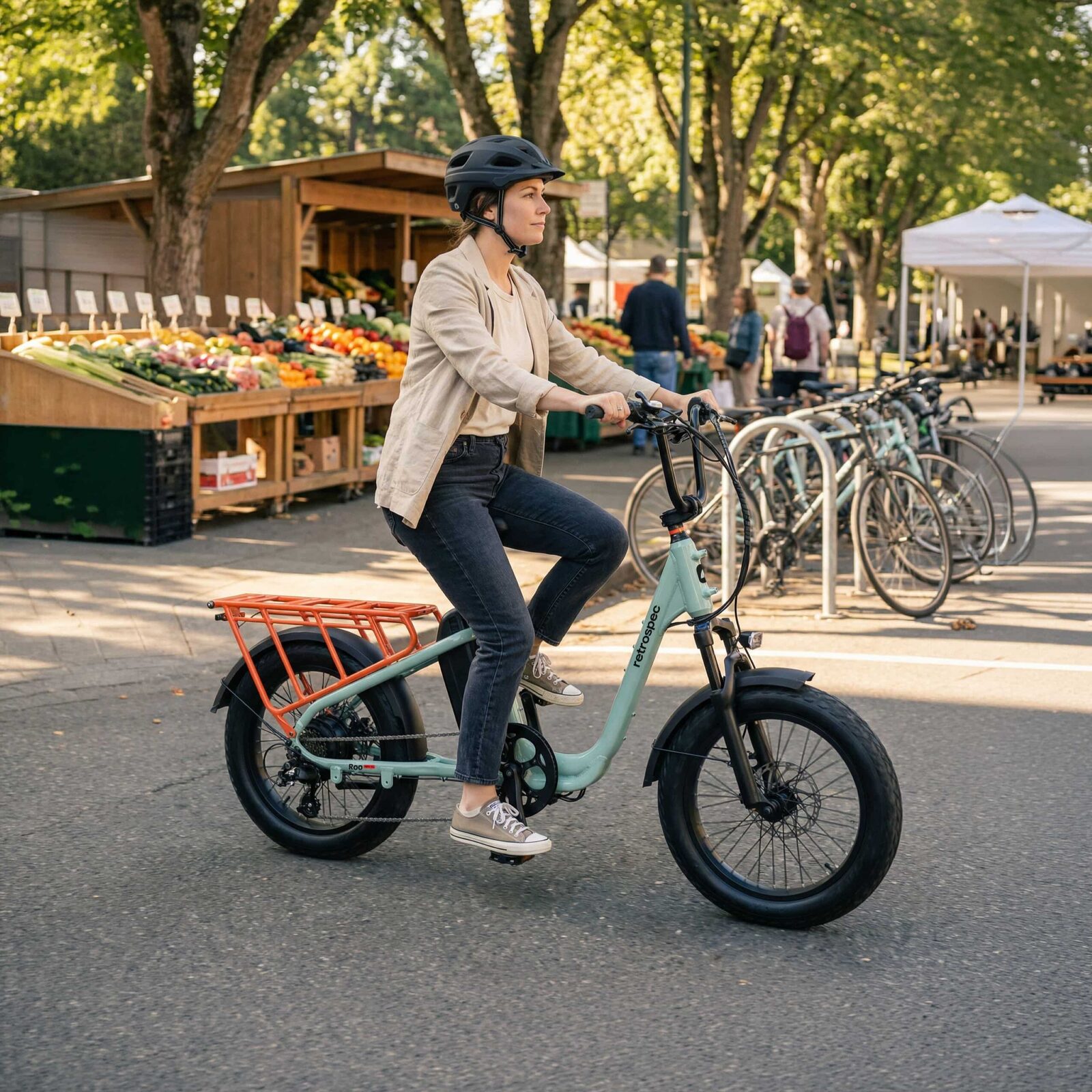 Rider on a Retrospec Roo Rev XL electric cargo bike in Mint at an outdoor market